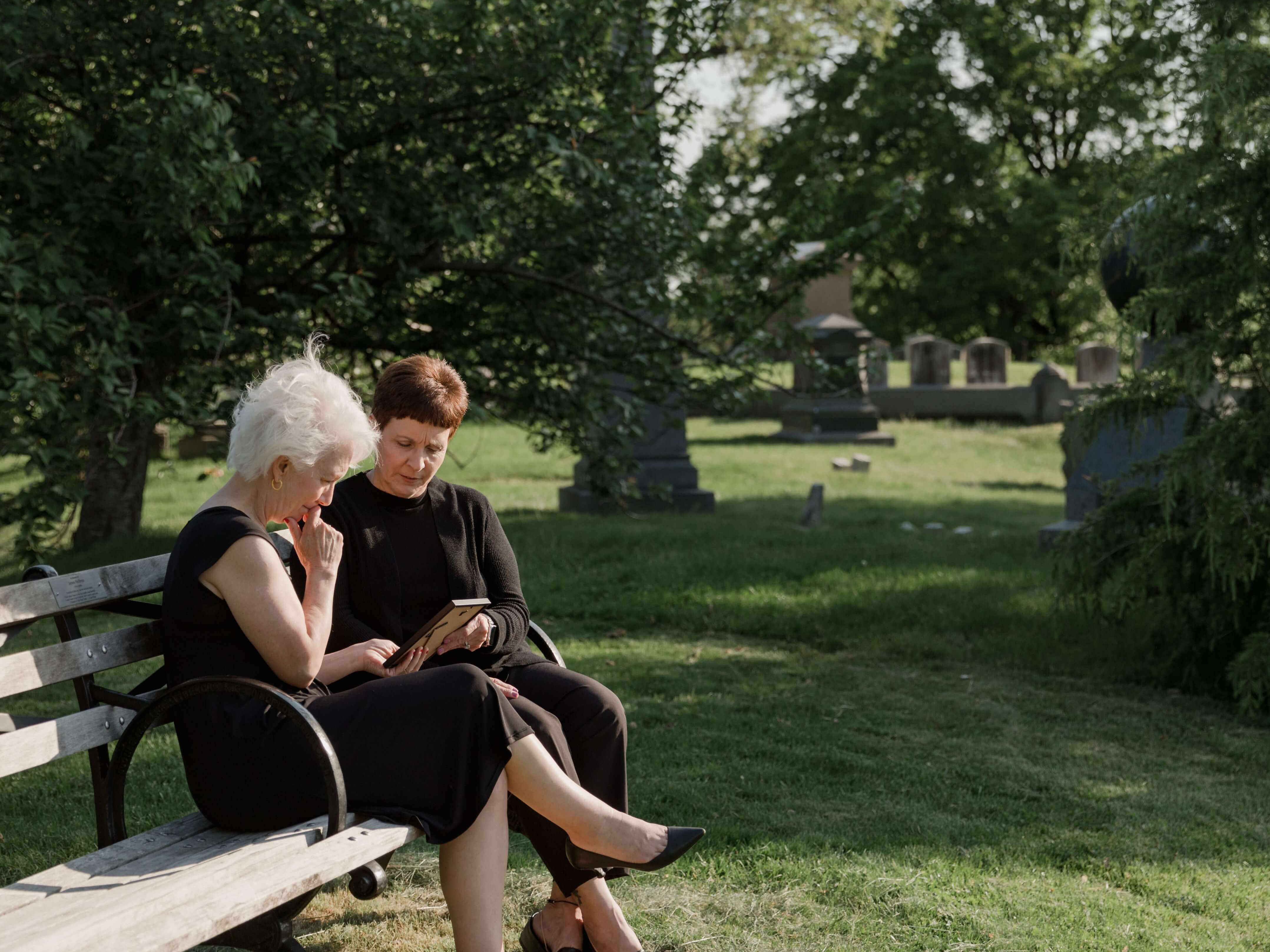 people grieving on a bench outside