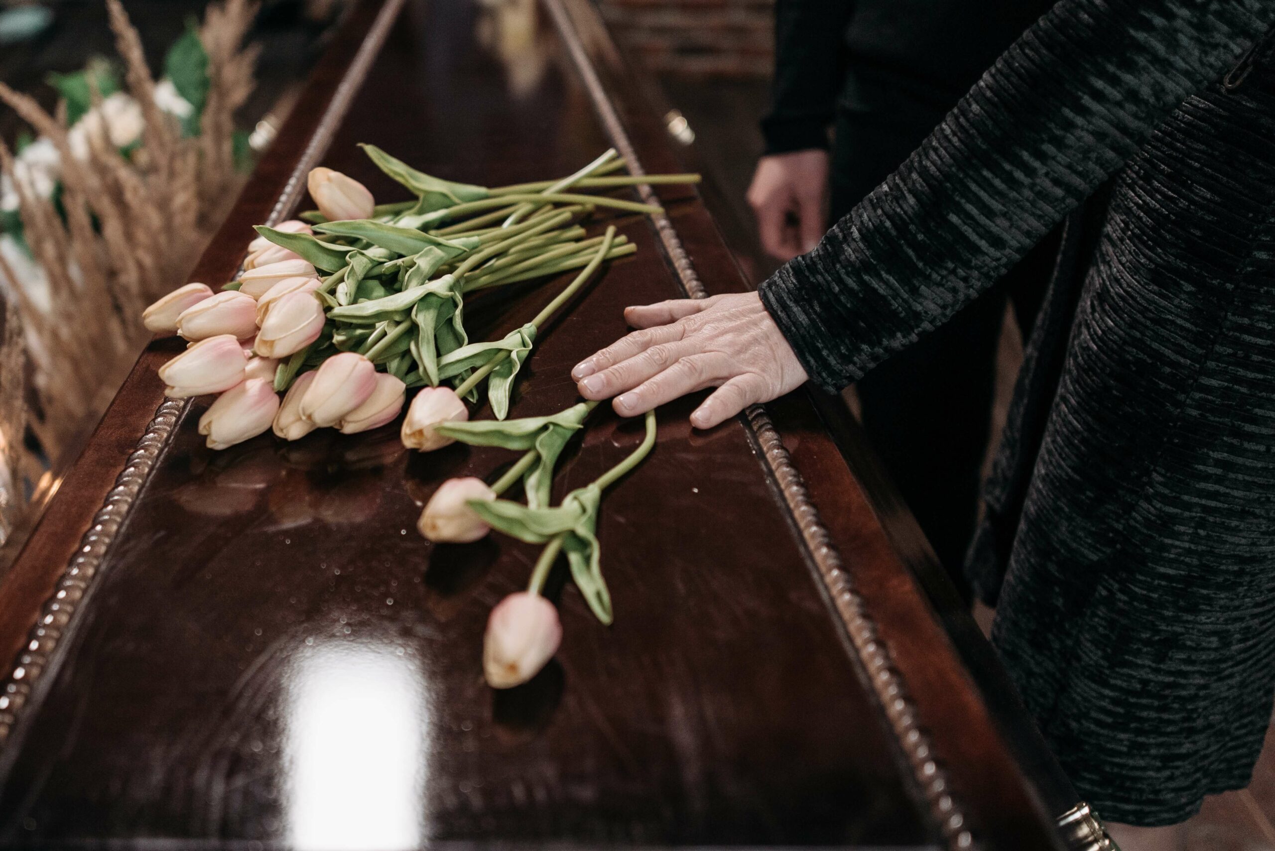 hand and flowers on a casket